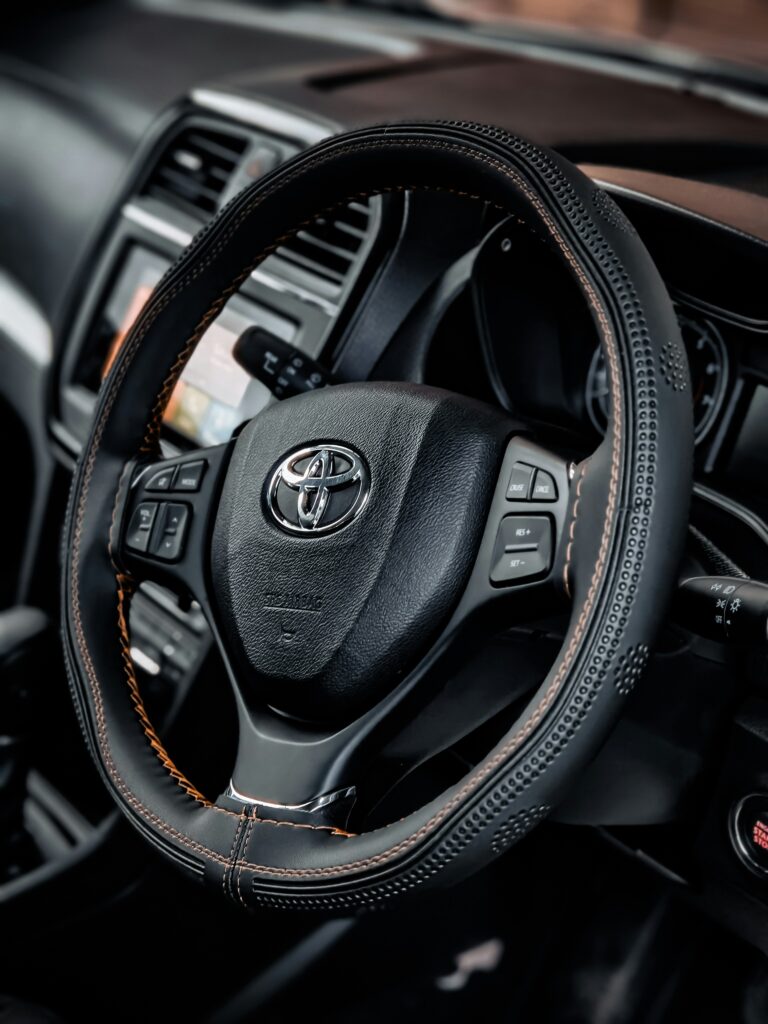 Modern car steering wheel with dashboard controls and a clean interior design.
